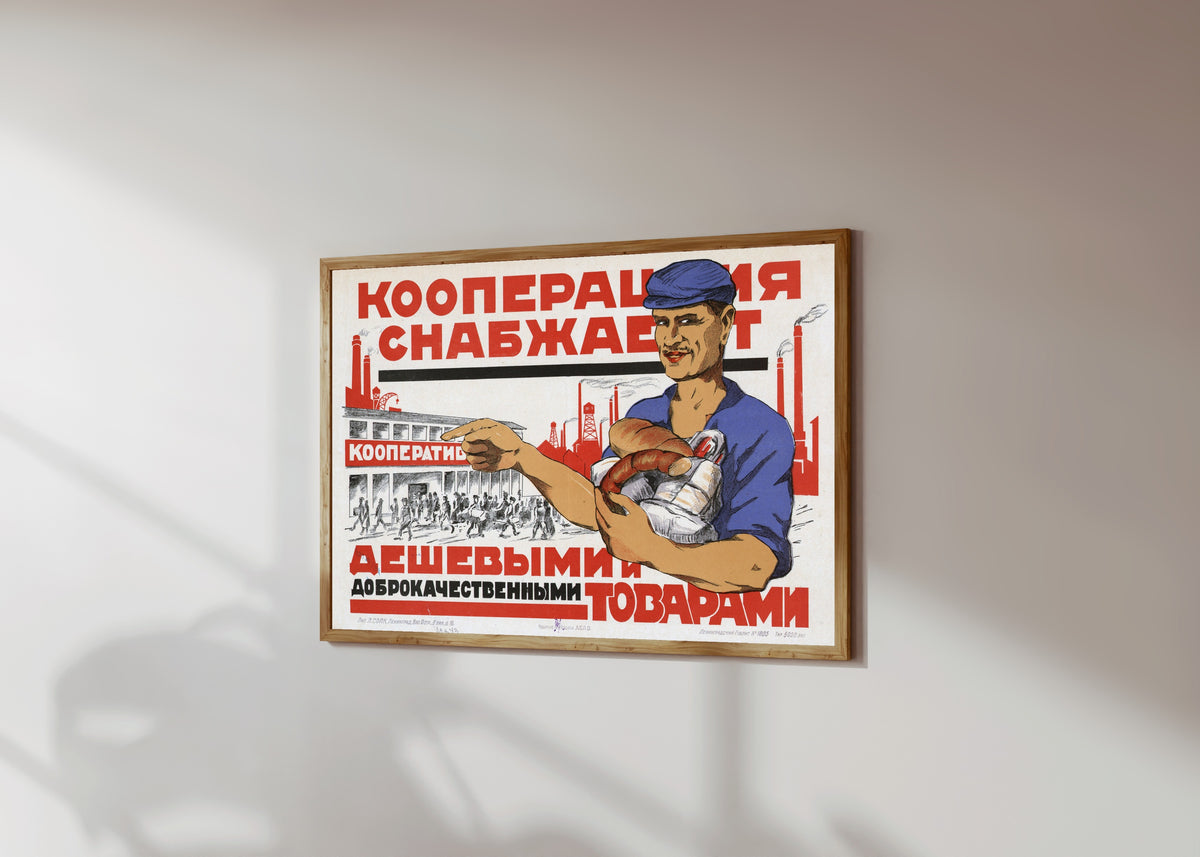 Framed art print of The cooperative supplies cheap and good-quality goods, in a light wood frame on a sunlit white wall, seen at a slight angle