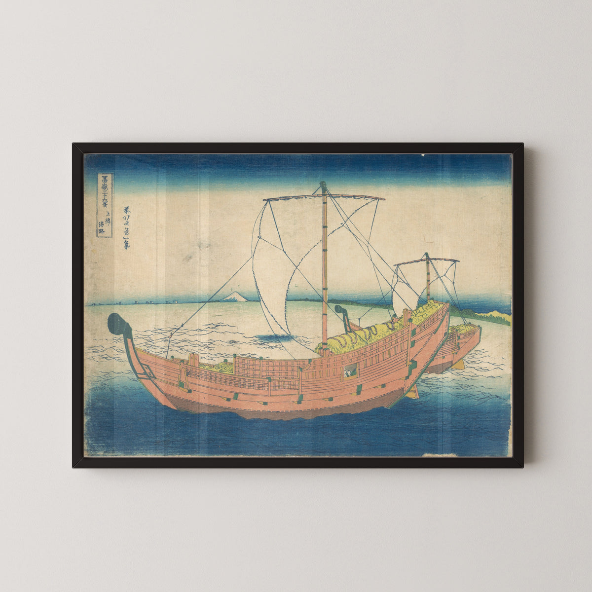 Framed art print of Thirty-six Views of Mount Fuji: At Sea off Kazusa by Katsushika Hokusai, in a black frame on a pale wall