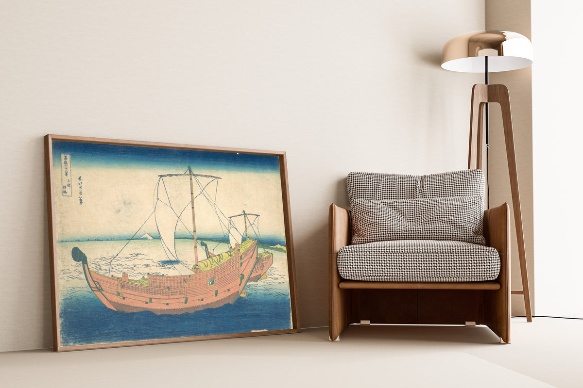 Framed art print of Thirty-six Views of Mount Fuji: At Sea off Kazusa by Katsushika Hokusai, leaning against a wall beside an armchair and a floor lamp