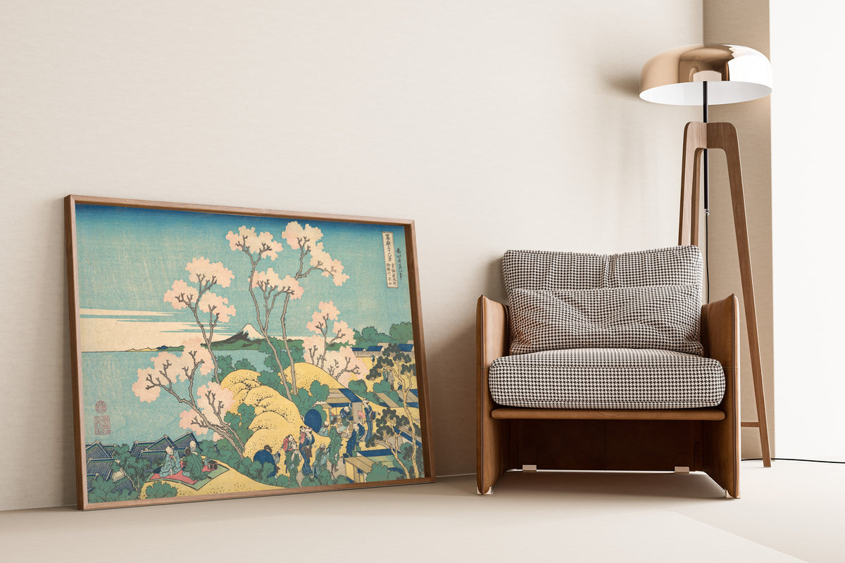 Framed art print of Thirty-six Views of Mount Fuji: Fuji from Gotenyama on… by Katsushika Hokusai, leaning against a wall beside an armchair and a floor lamp