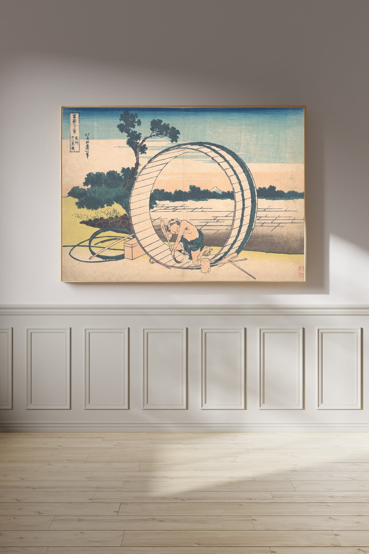 Framed art print of Thirty-six Views of Mount Fuji: Fujimigahara in Owari Province by Katsushika Hokusai, on a panelled wall in afternoon light