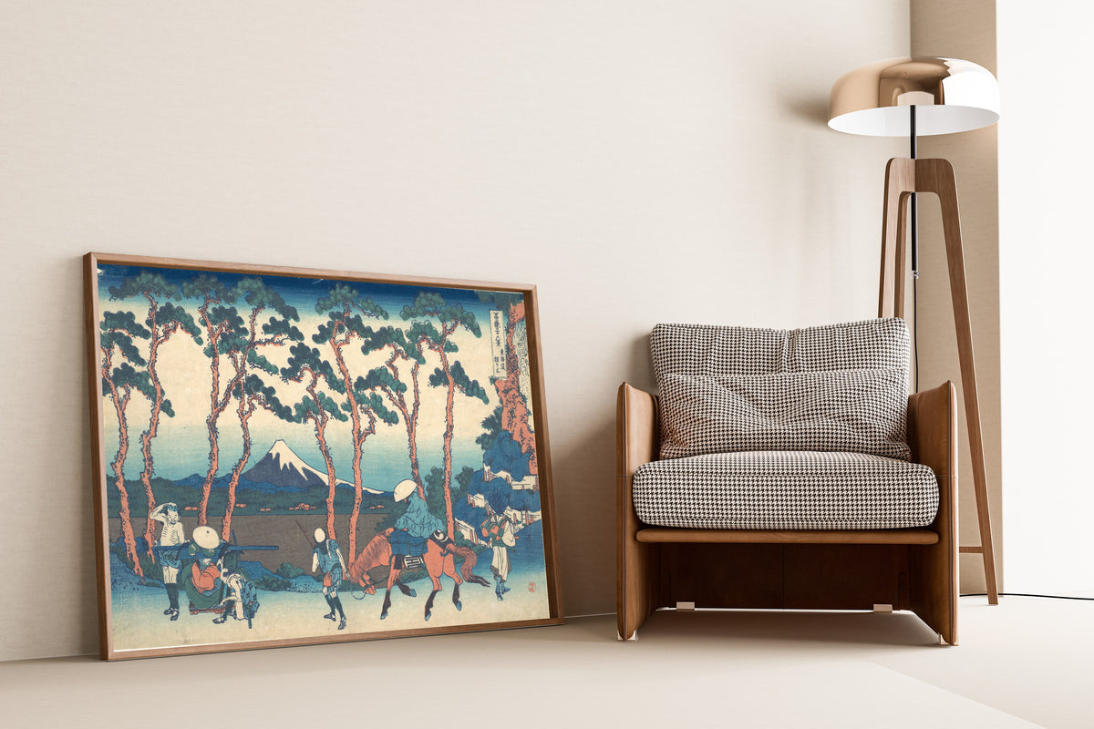 Framed art print of Thirty-six Views of Mount Fuji: Hodogaya on the Tōkaidō by Katsushika Hokusai, leaning against a wall beside an armchair and a floor lamp
