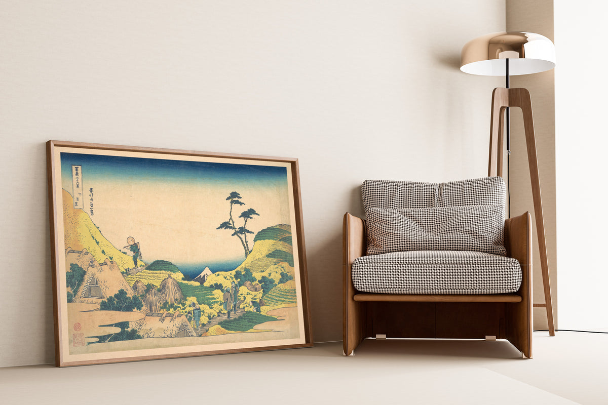 Framed art print of Thirty-six Views of Mount Fuji: Lower Meguro by Katsushika Hokusai, leaning against a wall beside an armchair and a floor lamp