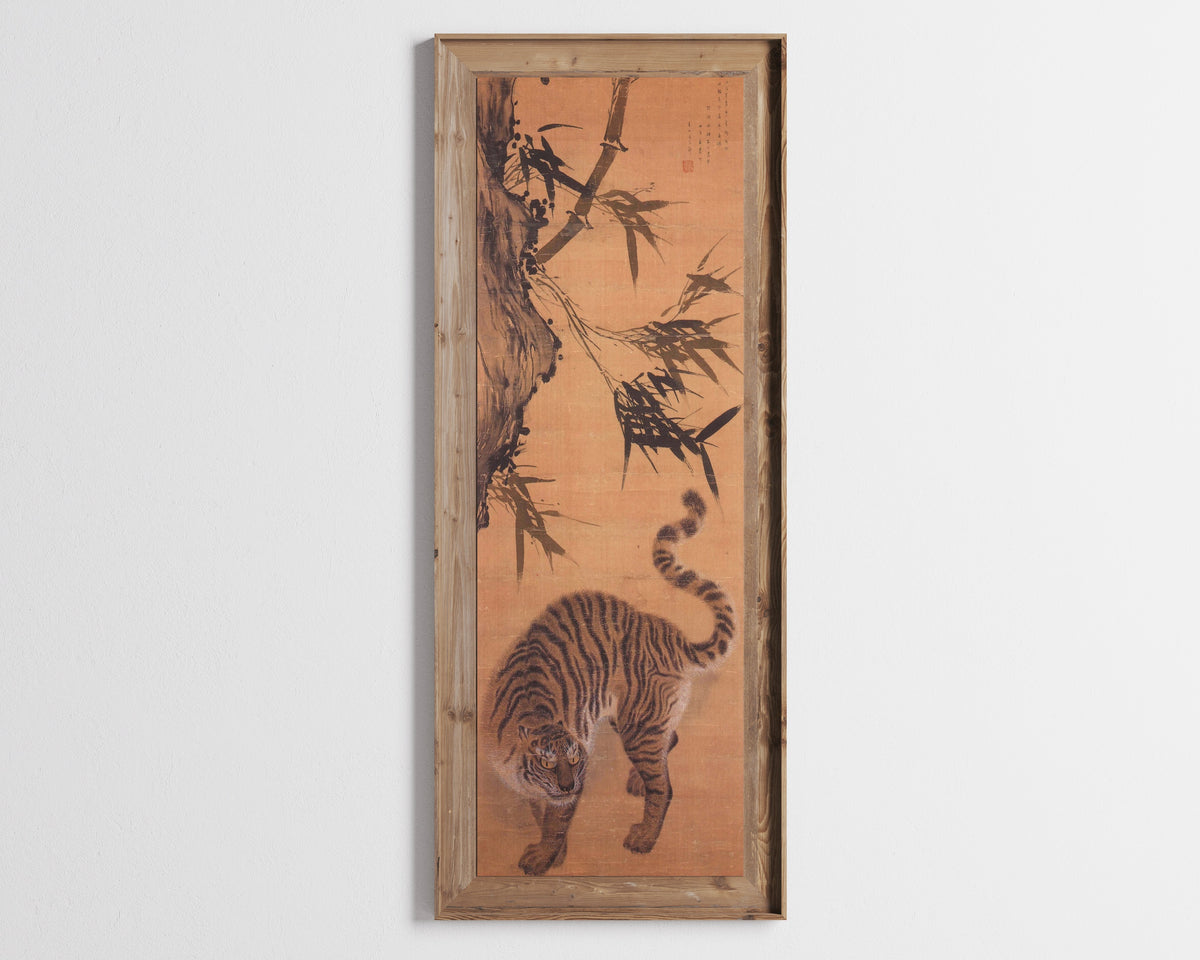 Framed art print of Tiger under Bamboo by Kim Hong-do (Danwon), in a tall wooden frame on a pale wall