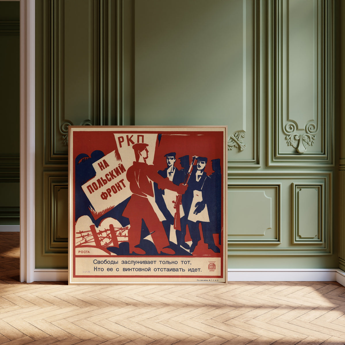 Framed art print of To the Polish front: only he deserves freedom who goes to… by Ivan Malyutin, leaning against olive-green panelling on a herringbone floor