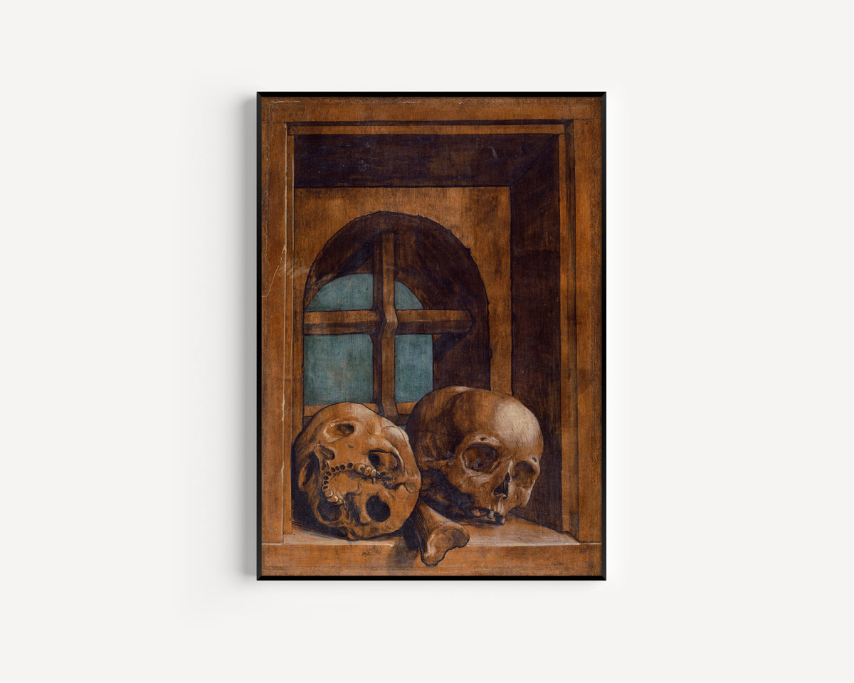 Framed art print of Two Skulls in a Window Niche by Hans Holbein the Younger, in a slim black frame on a plain white wall