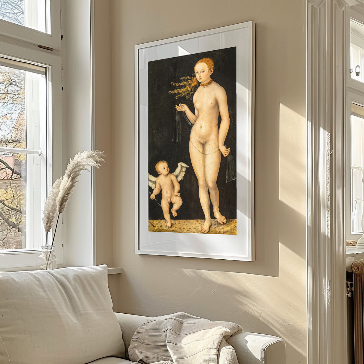 Framed art print of Venus and Cupid by Lucas Cranach the Elder, in a sunlit living room above a sofa