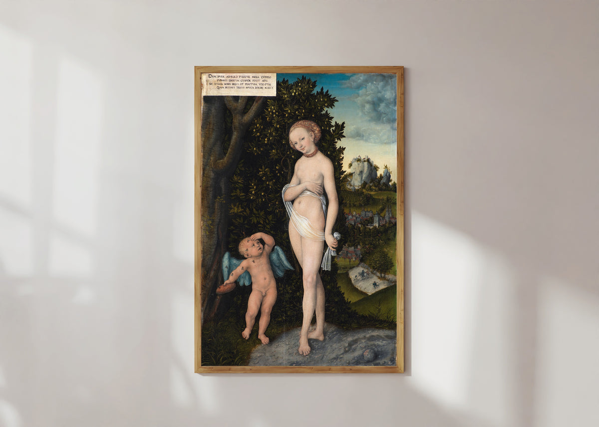 Framed art print of Venus with Cupid Stealing Honey by Lucas Cranach the Elder, in a light wood frame on a sunlit white wall