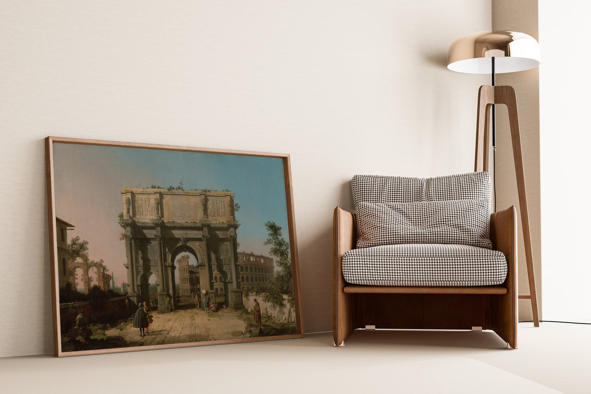 Framed art print of View of the Arch of Constantine with the Colosseum by Canaletto, leaning against a wall beside an armchair and a floor lamp