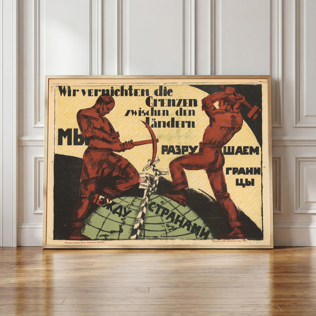 Framed art print of We are destroying the borders between countries, in a light wood frame leaning against a panelled white wall