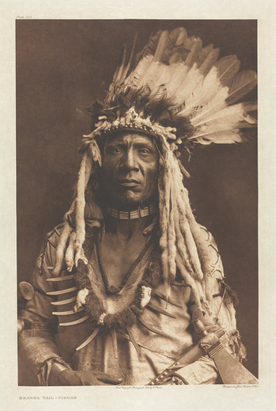 Edward S. Curtis — Weasel Tail – Piegan | Vintage Photograph Print shown to scale on a wall above a sofa