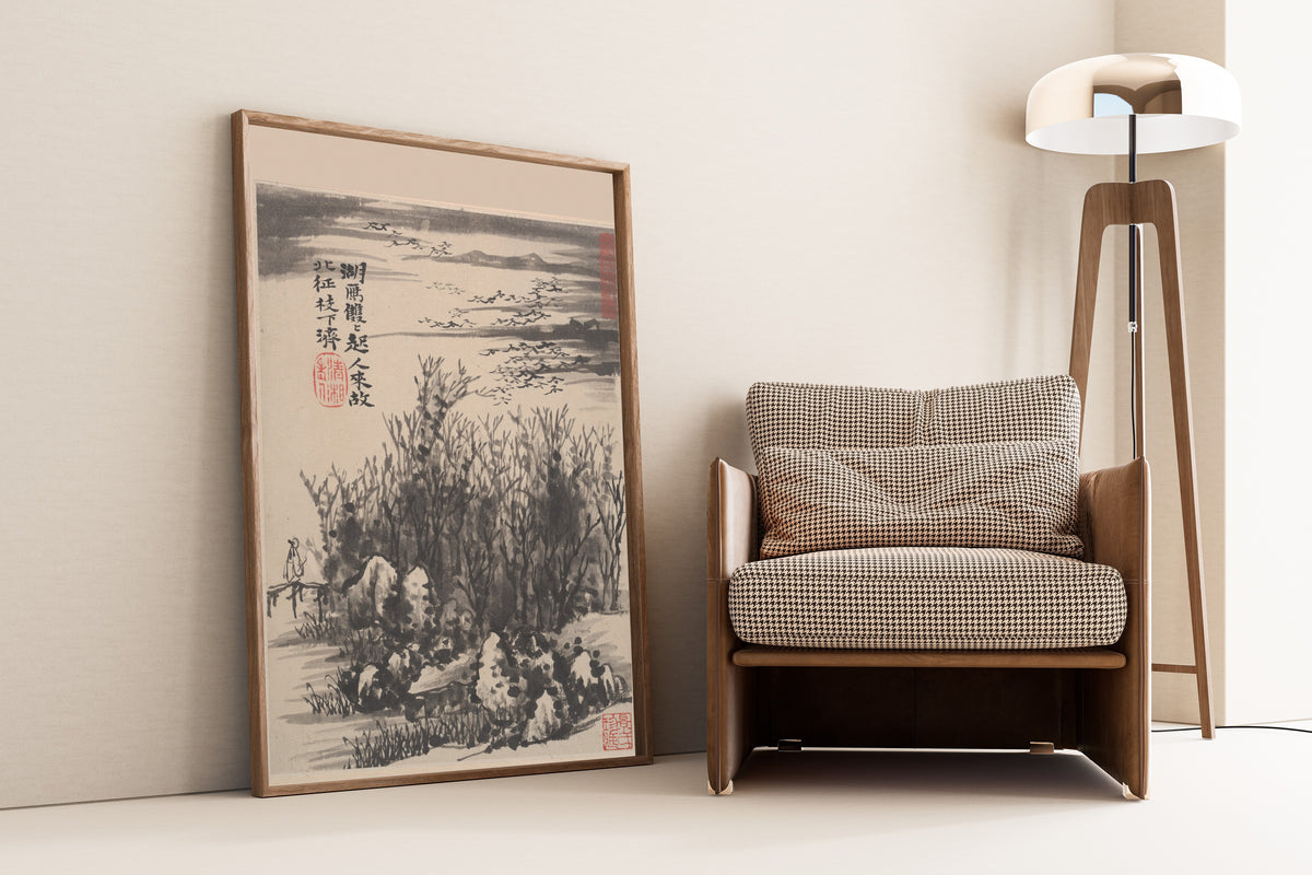 Framed art print of Wilderness Colors (Wild Geese over the Lake) by Shitao, leaning against a wall beside an armchair and a floor lamp