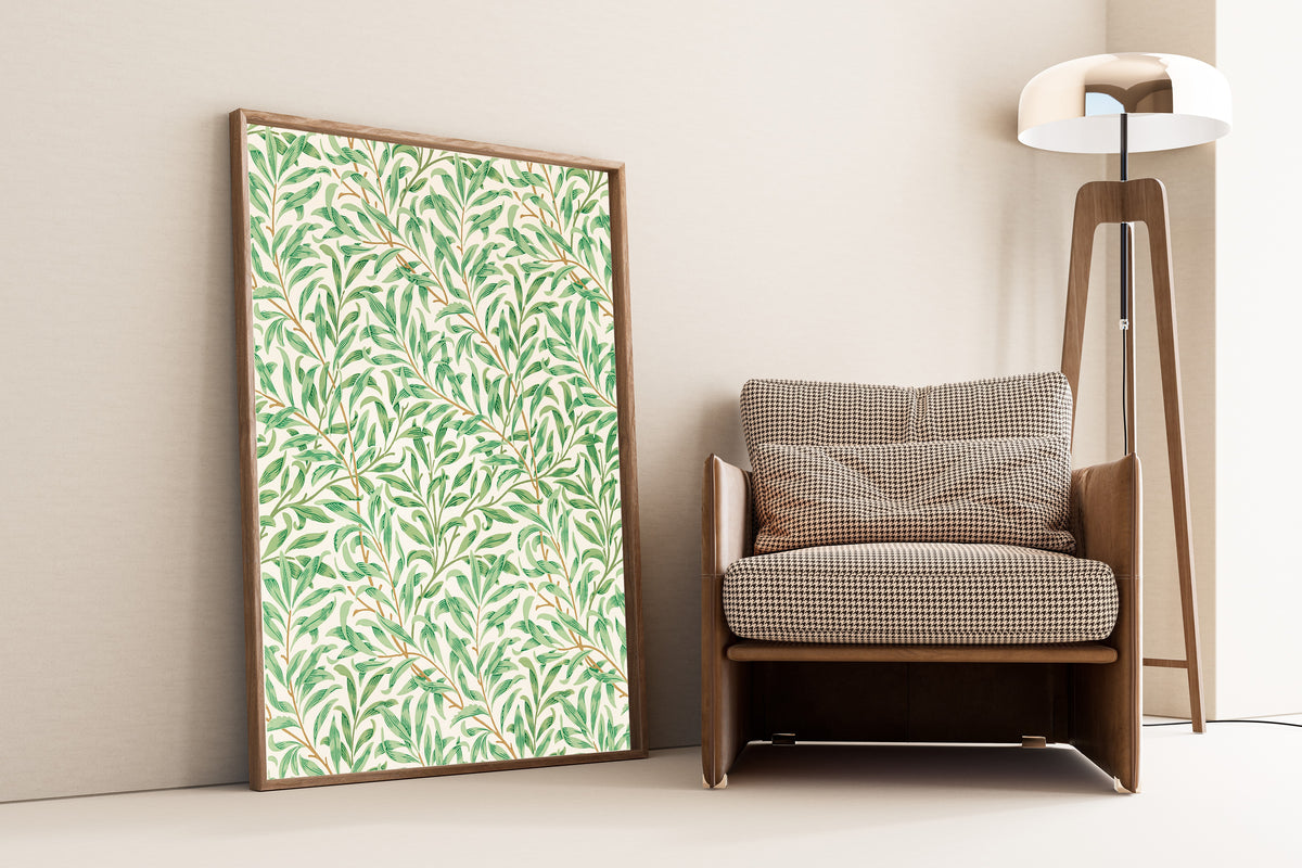 Framed art print of Willow Bough by William Morris, leaning against a wall beside an armchair and a floor lamp