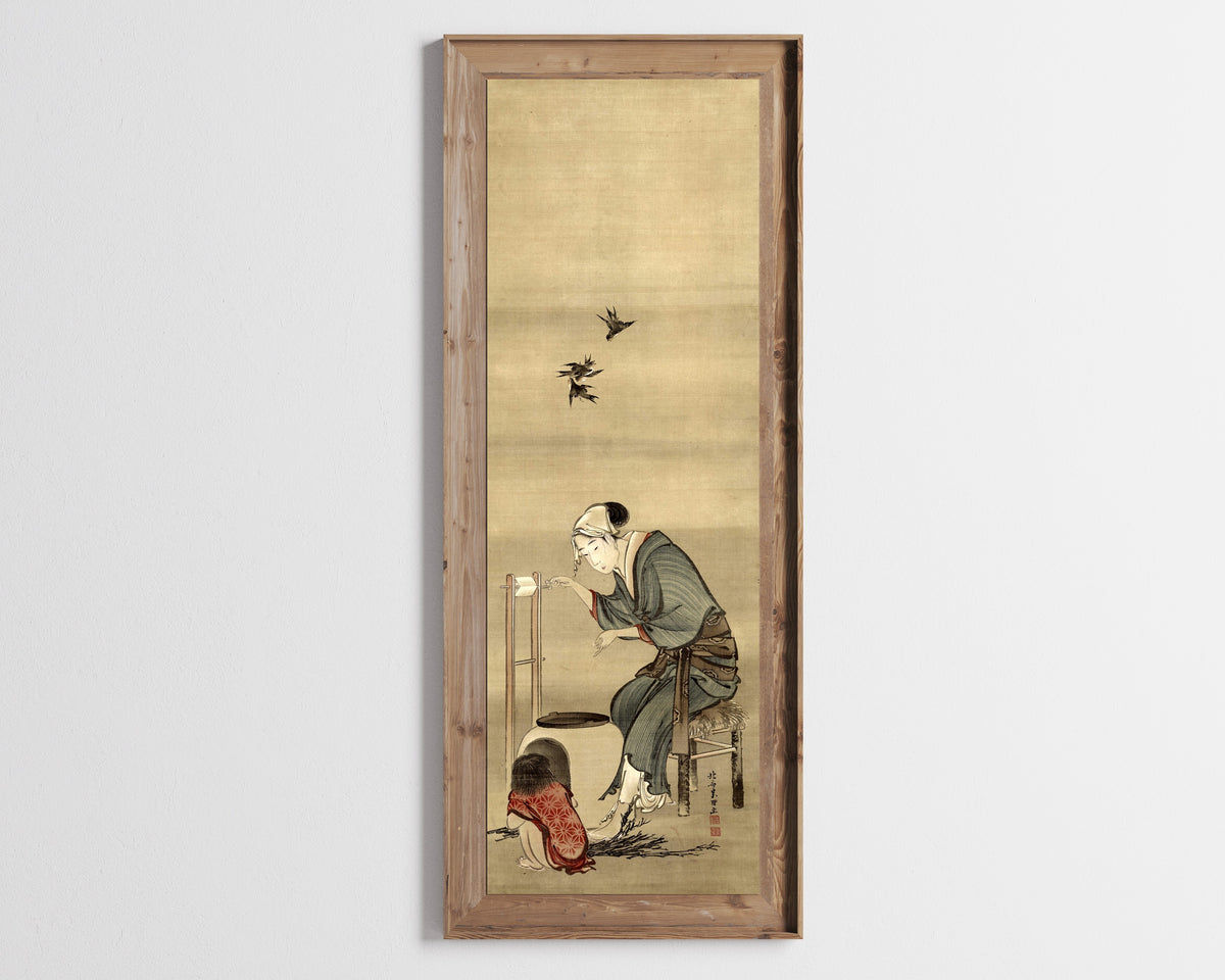 Framed art print of Woman Spinning Silk by Katsushika Hokusai, in a tall wooden frame on a pale wall