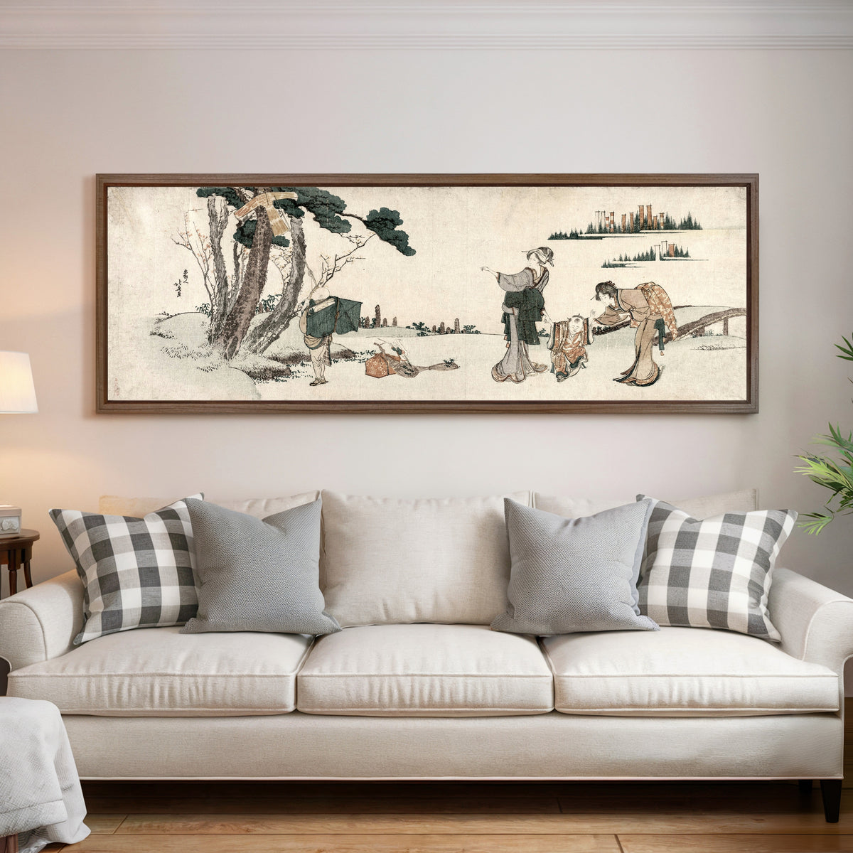 Framed art print of Women Distracting a Child whose Kite is caught in a Tree by Katsushika Hokusai, above a cream sofa