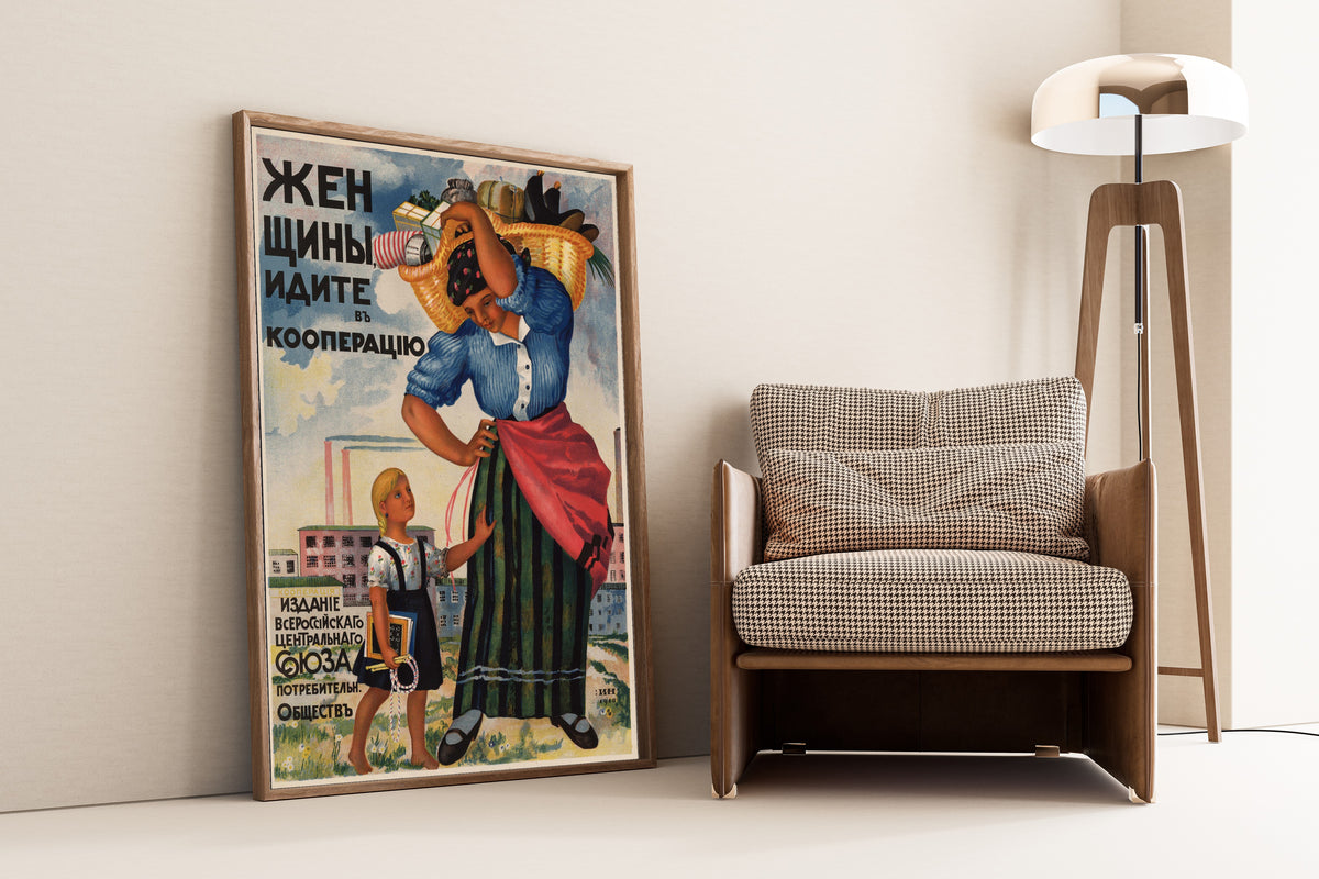 Framed art print of Women, Join the Cooperative by Ignaty Nivinsky, leaning against a wall beside an armchair and a floor lamp