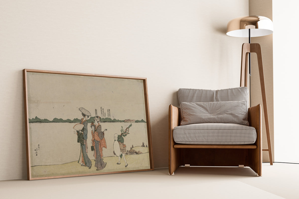 Framed art print of Women and Children Walking Along the Sumida River by Katsushika Hokusai, leaning against a wall beside an armchair and a floor lamp