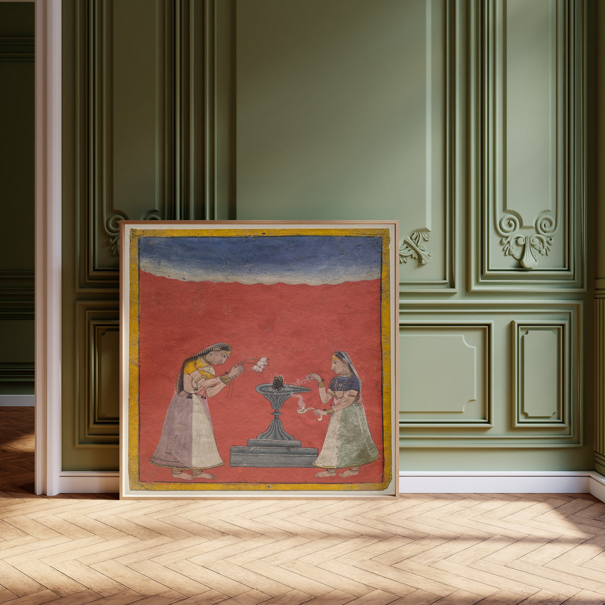 Framed art print of Women worshiping a Shiva linga: Devagandhari Ragini of… by Pahari school, leaning against olive-green panelling on a herringbone floor