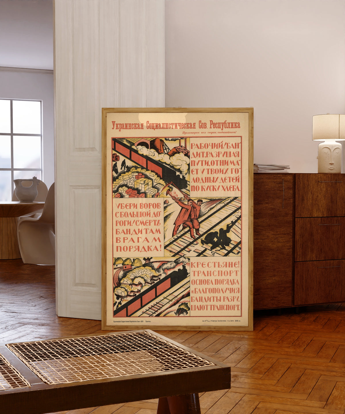 Framed art print of Worker! The bandit, wrecking the rails, takes a piece of bread from…, in a light wood frame leaning in a warm room with a parquet floor