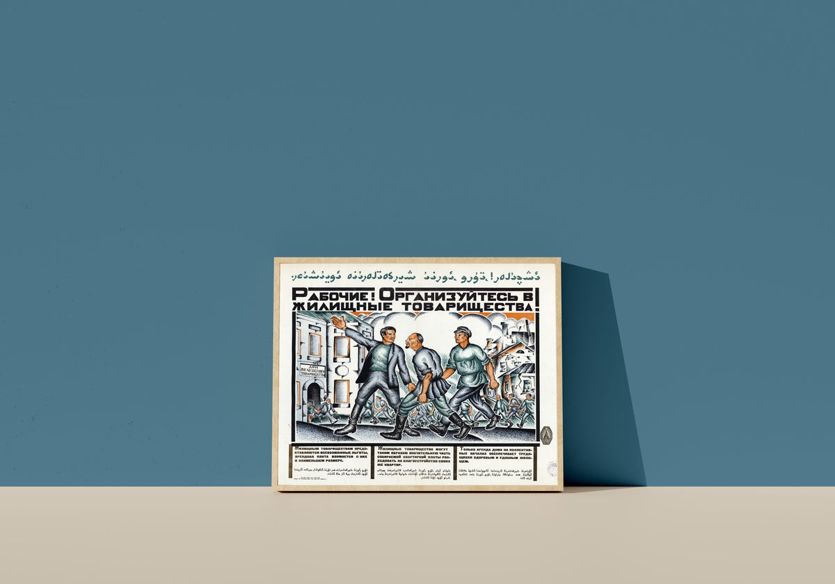 Framed art print of Workers! Organise into housing cooperatives!, in a light wood frame leaning on a blue wall