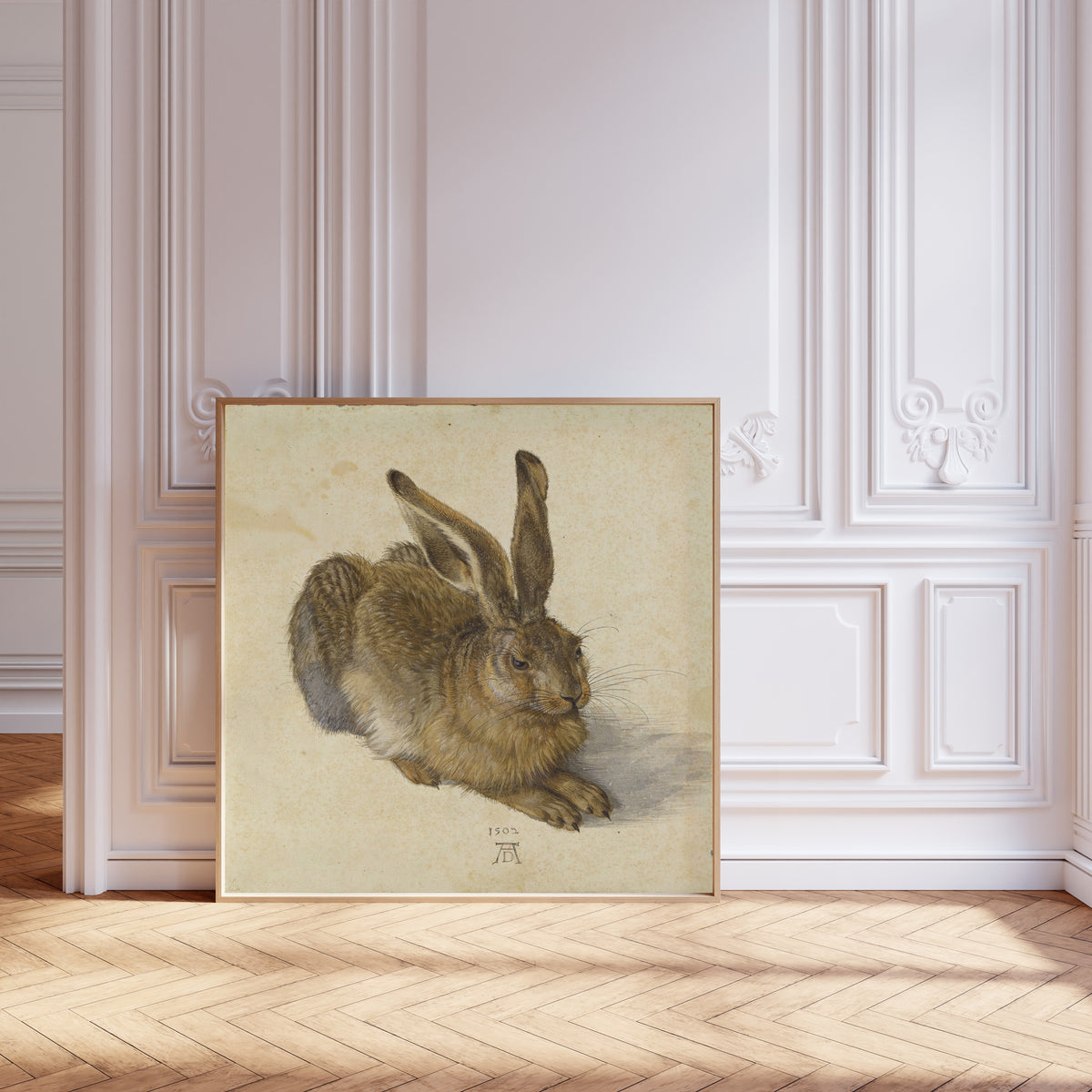 Framed art print of Young Hare by Albrecht Dürer, leaning against pale pink panelling on a herringbone floor