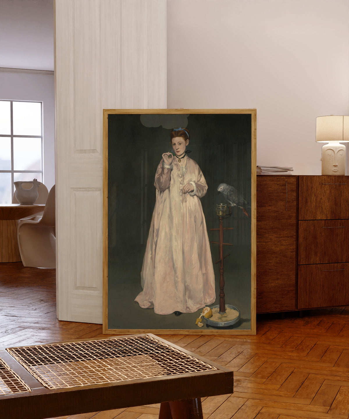 Framed art print of Young Lady in 1866 by Édouard Manet, in a light wood frame leaning in a warm room with a parquet floor