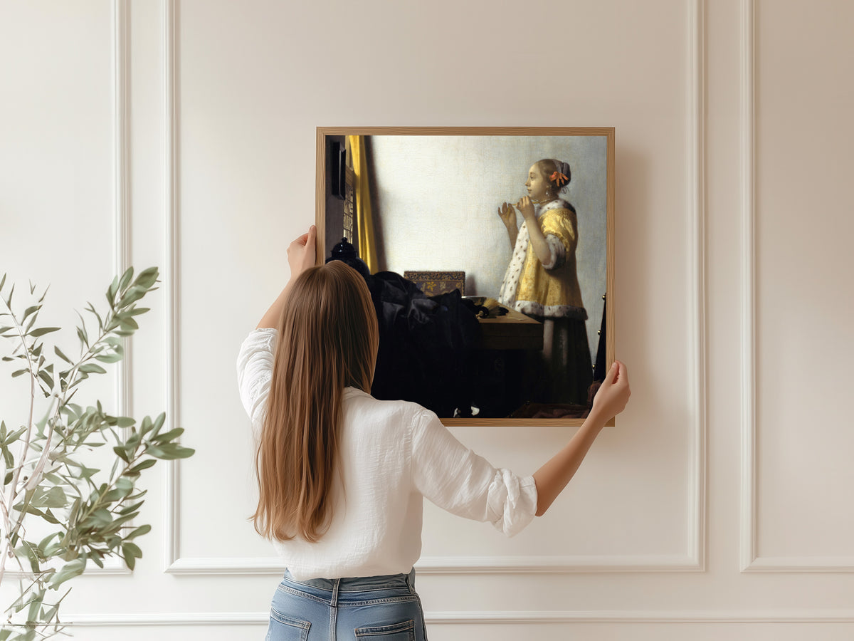 Framed art print of Young Woman with a Pearl Necklace by Johannes Vermeer, hung on a panelled wall