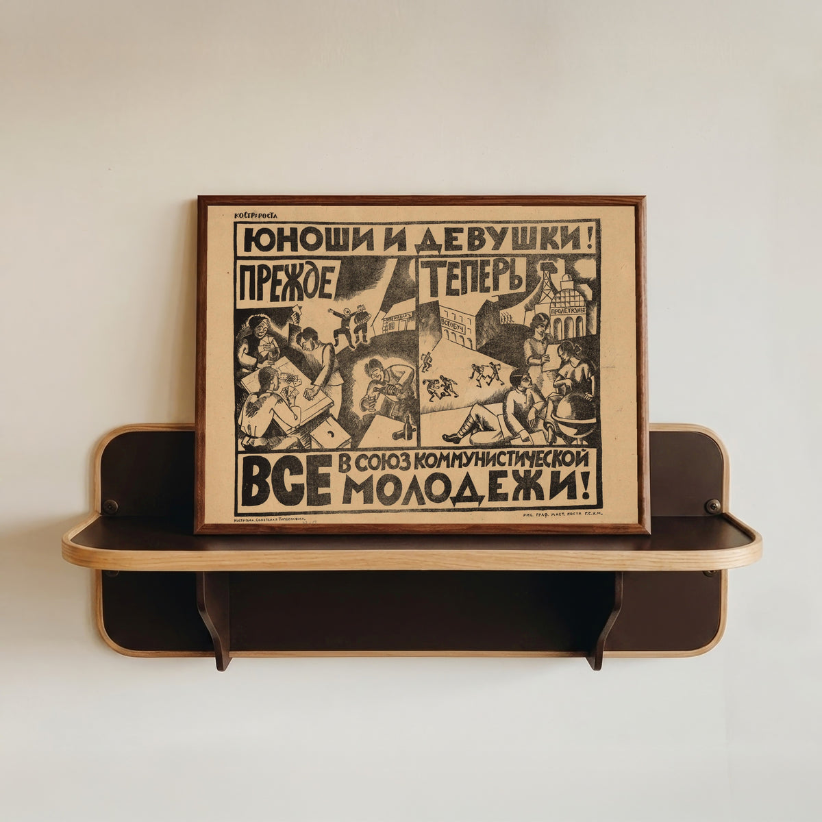Framed art print of Young men and women! Everyone into the Communist Youth League! by Nikolai Kupreyanov, in a dark wood frame resting on a wall shelf