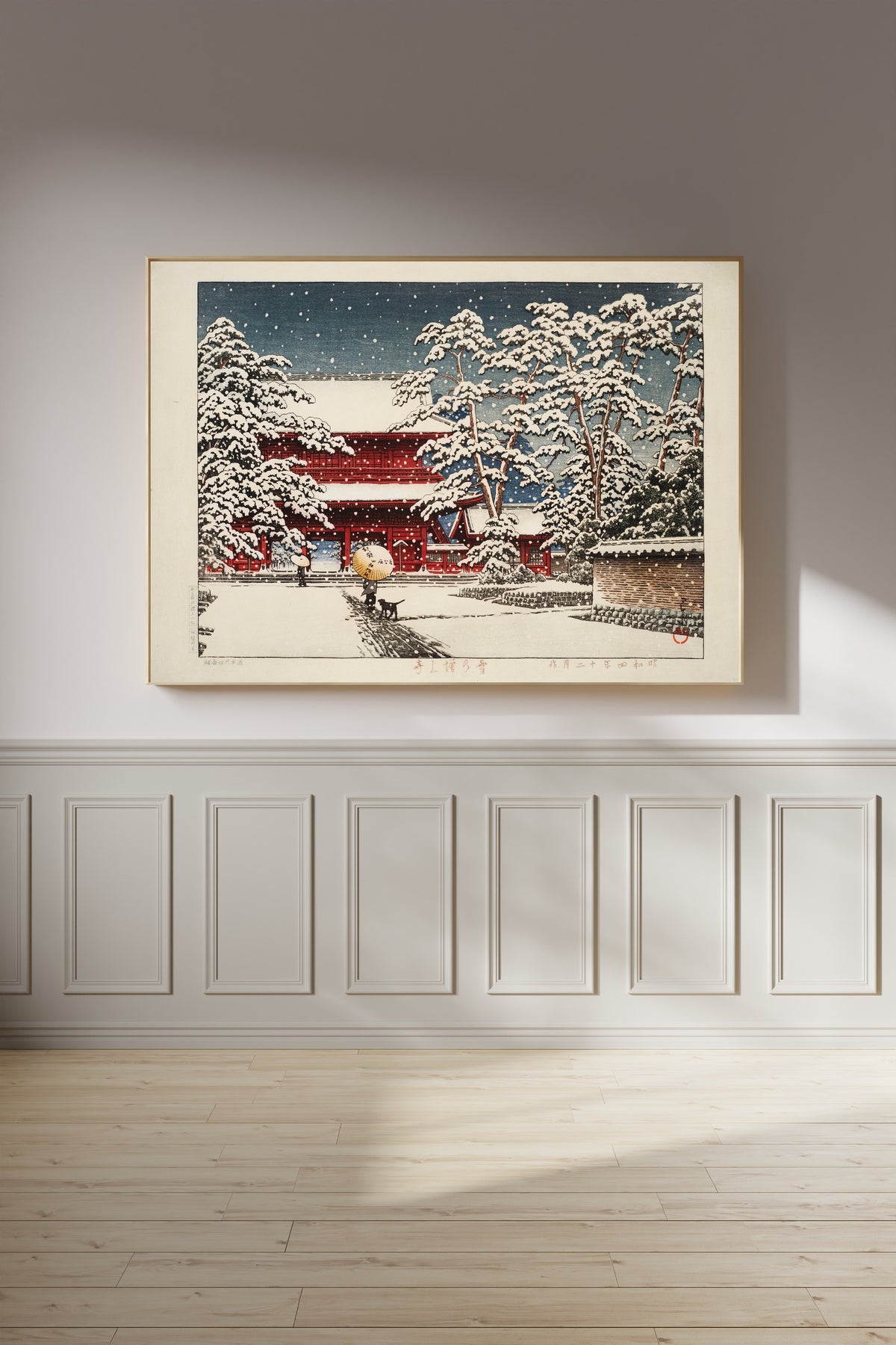Framed art print of Zojoji Temple in Snow by Kawase Hasui, on a panelled wall in afternoon light