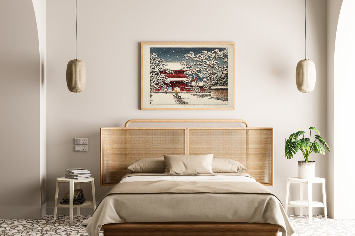 Framed art print of Zojoji Temple in Snow by Kawase Hasui, above a cane-headboard bed