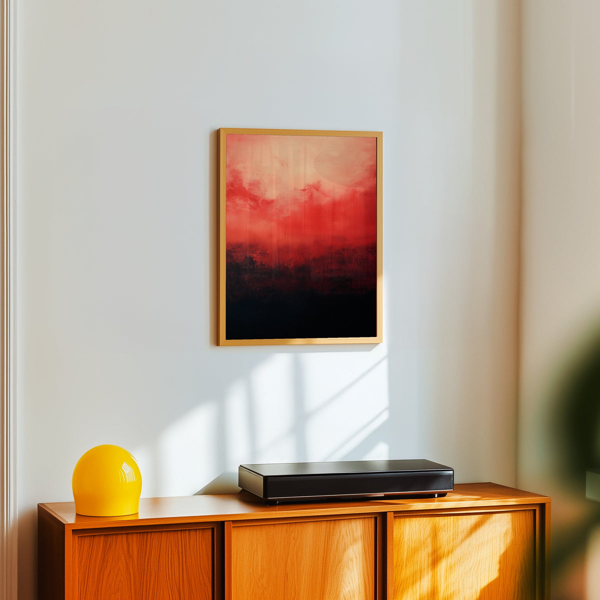 Framed art print of Black and Red (Colour Field) by After Mark Rothko, in a light wood frame on a white wall above an orange sideboard