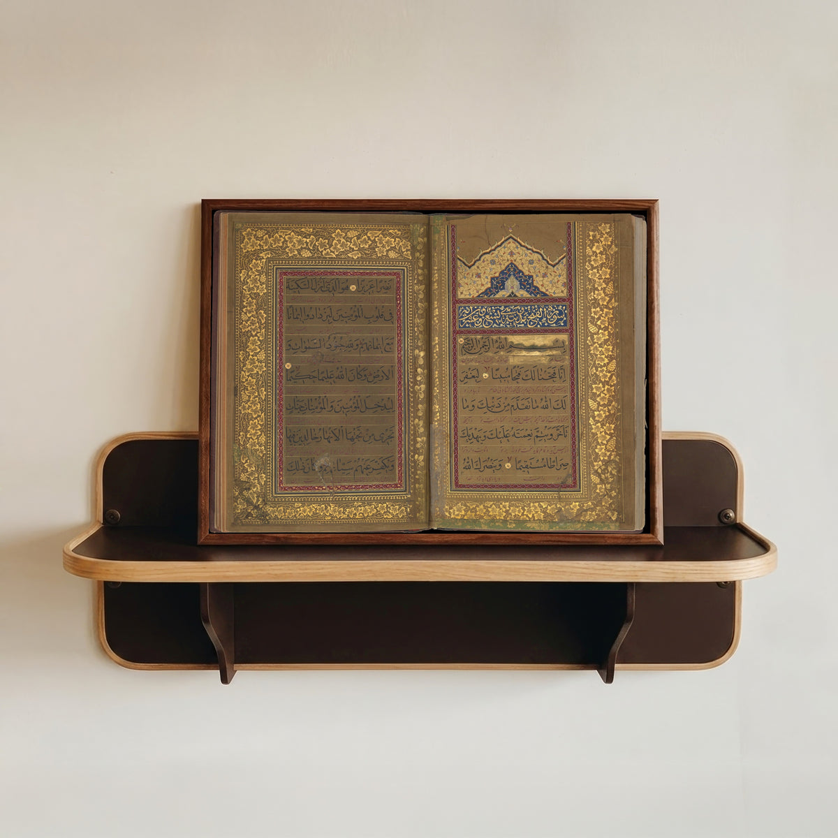 Framed art print of Book of Prayers: Opening of Surat al-Fath by Ahmad Nairizi, in a dark wood frame resting on a wall shelf