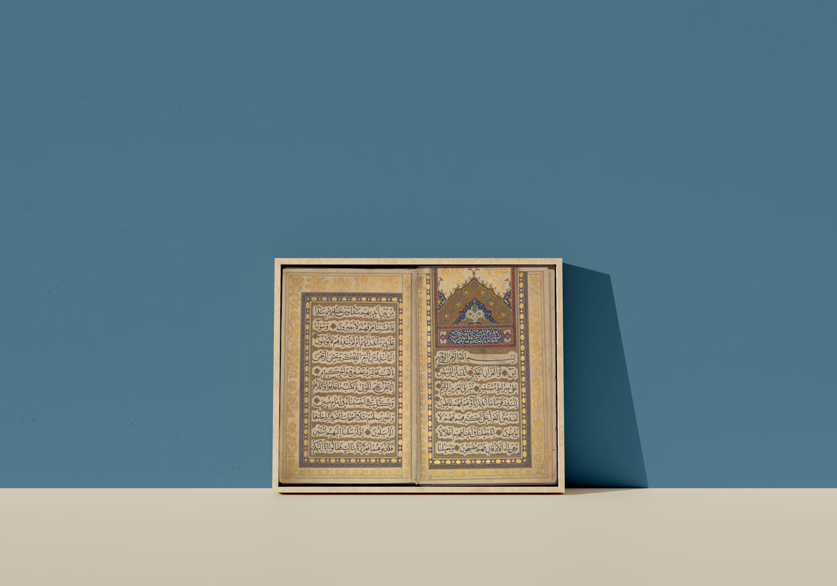 Framed art print of Book of Prayers: Opening of Surat Ya-Sin by Ahmad Nairizi, in a light wood frame leaning on a blue wall