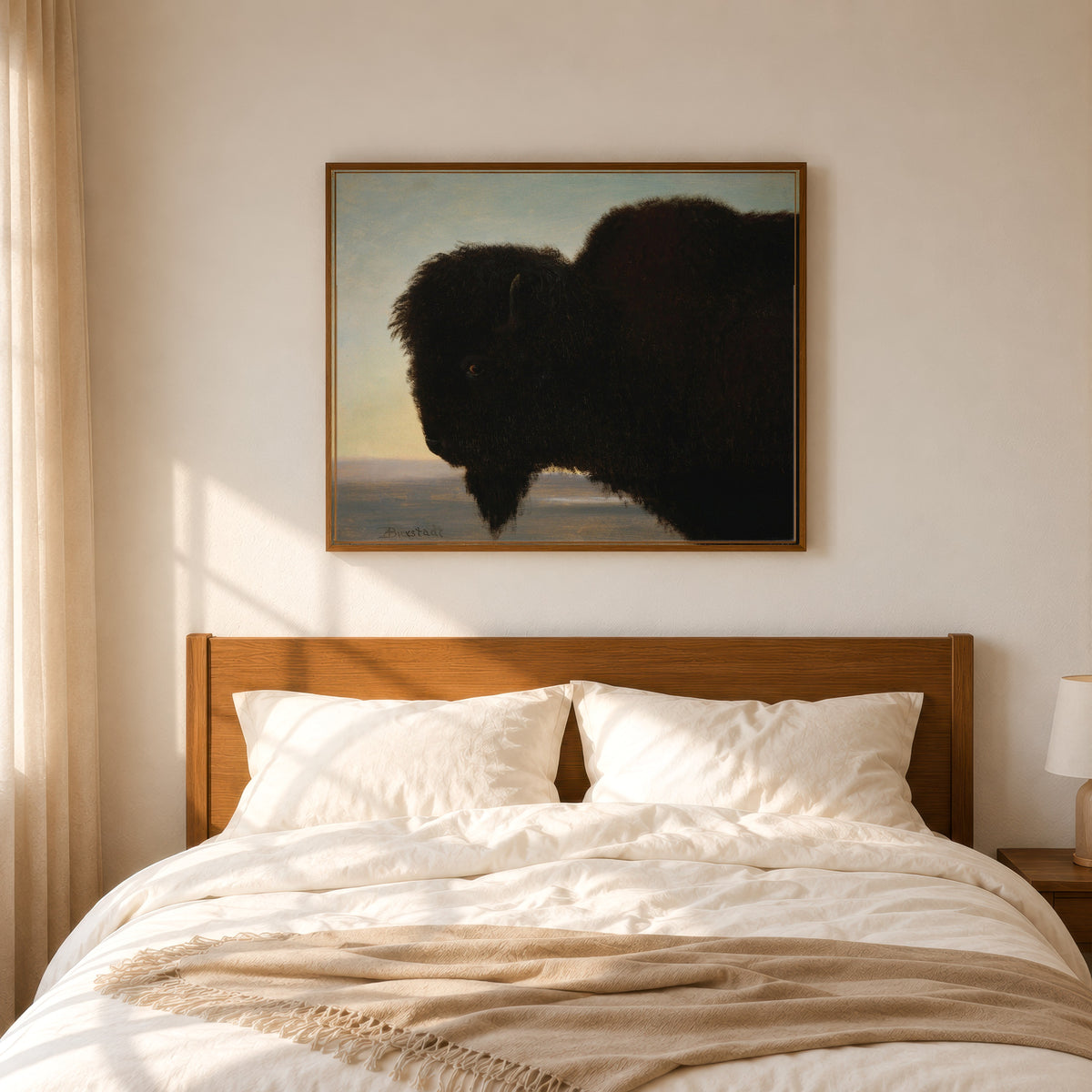 Framed art print of Buffalo by Albert Bierstadt, in a slim wood frame above a bed in a sunlit bedroom