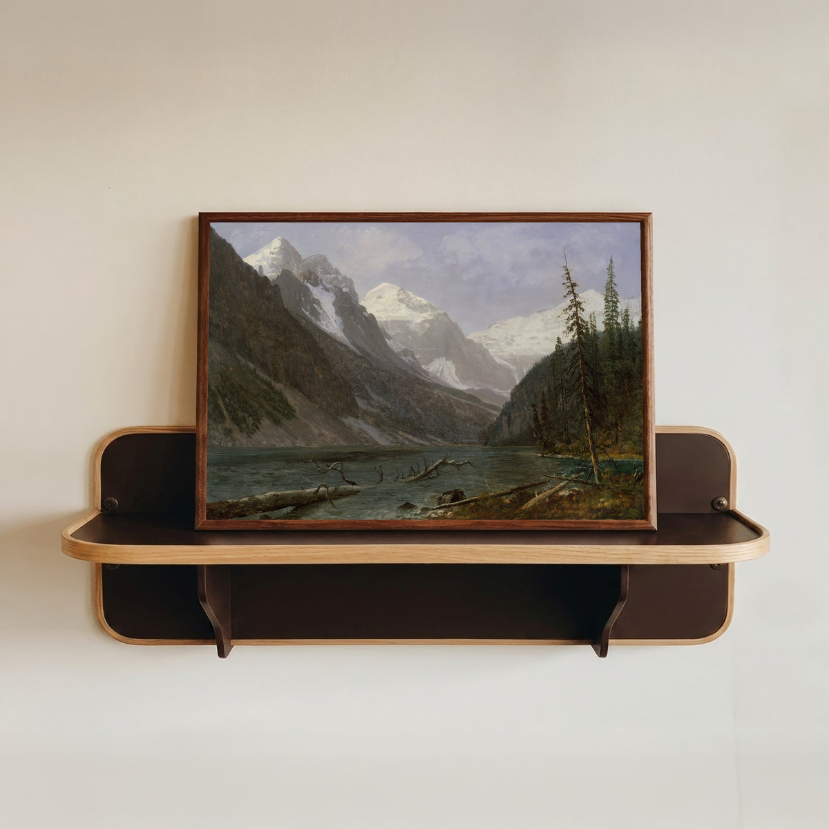 Framed art print of Canadian Rockies (Lake Louise) by Albert Bierstadt, in a dark wood frame resting on a wall shelf