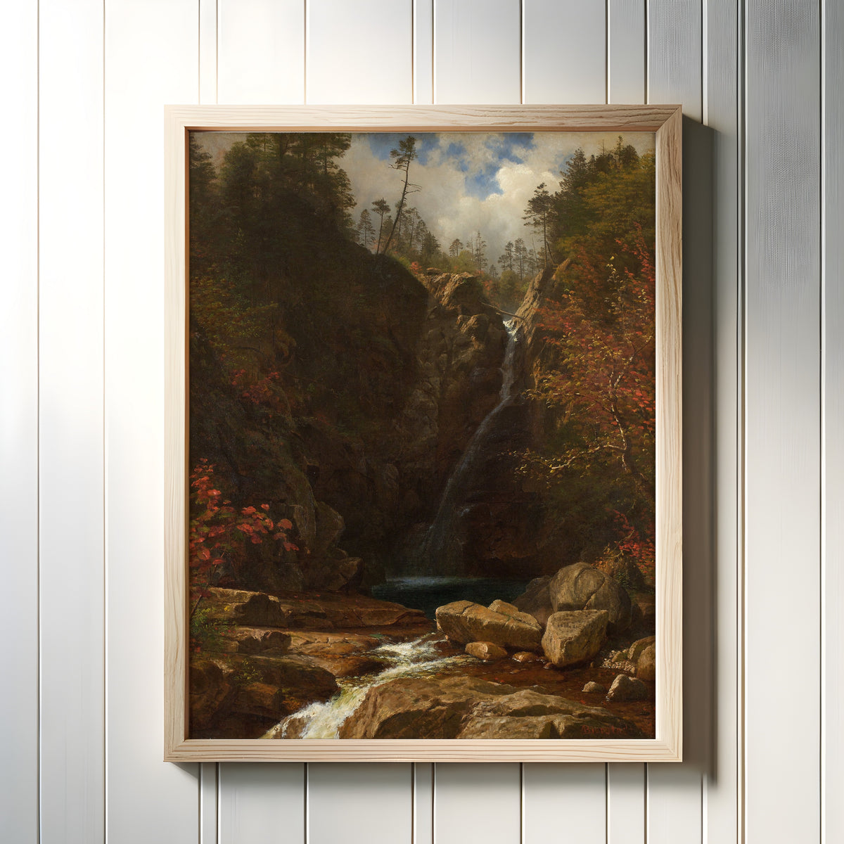 Framed art print of Glen Ellis Falls by Albert Bierstadt, in a light wood frame on a white panelled wall