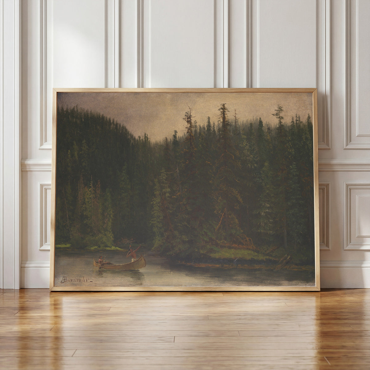 Framed art print of Indian Hunters in Canoe by Albert Bierstadt, in a light wood frame leaning against a panelled white wall