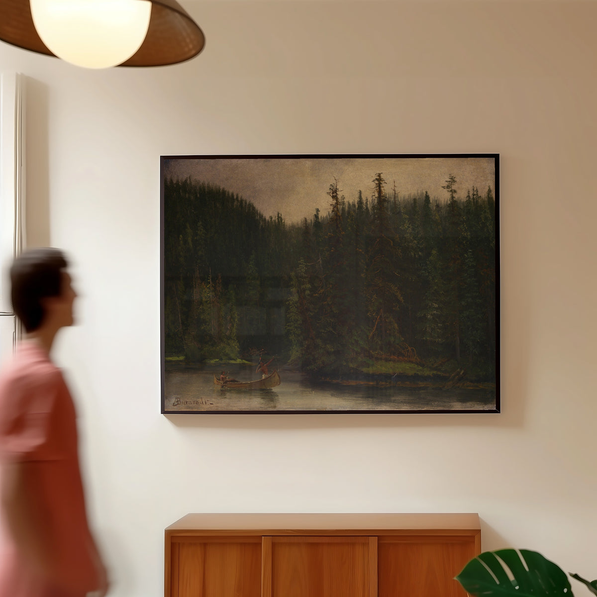 Framed art print of Indian Hunters in Canoe by Albert Bierstadt, in a slim black frame on a warm wall in a sunlit room