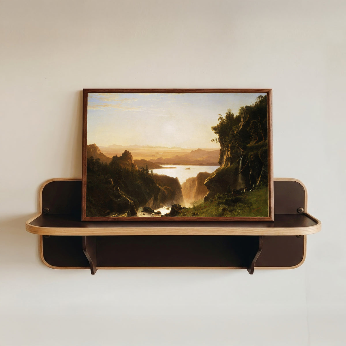 Framed art print of Island Lake by Albert Bierstadt, in a dark wood frame resting on a wall shelf