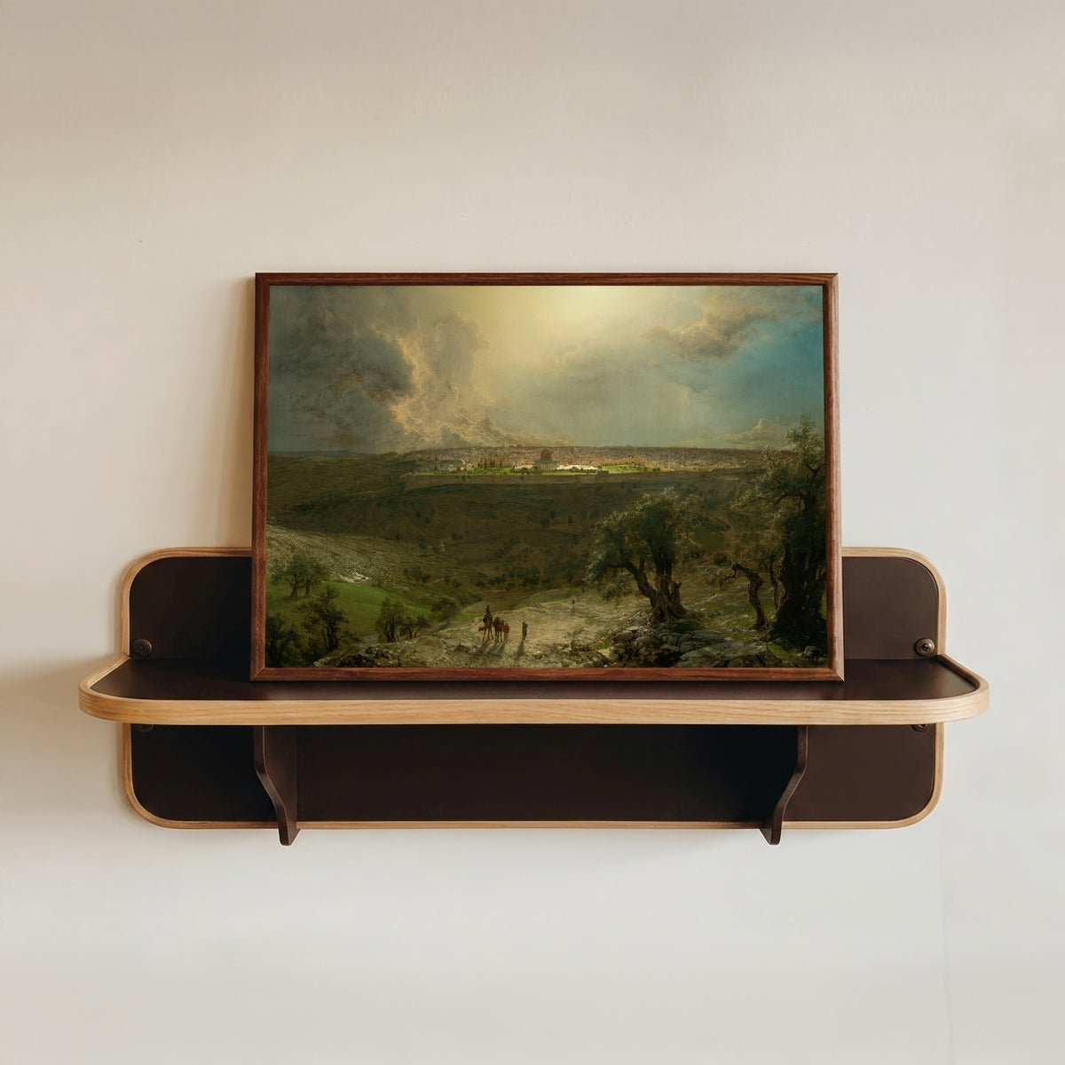 Framed art print of Jerusalem from the Mount of Olives by Albert Bierstadt, in a dark wood frame resting on a wall shelf
