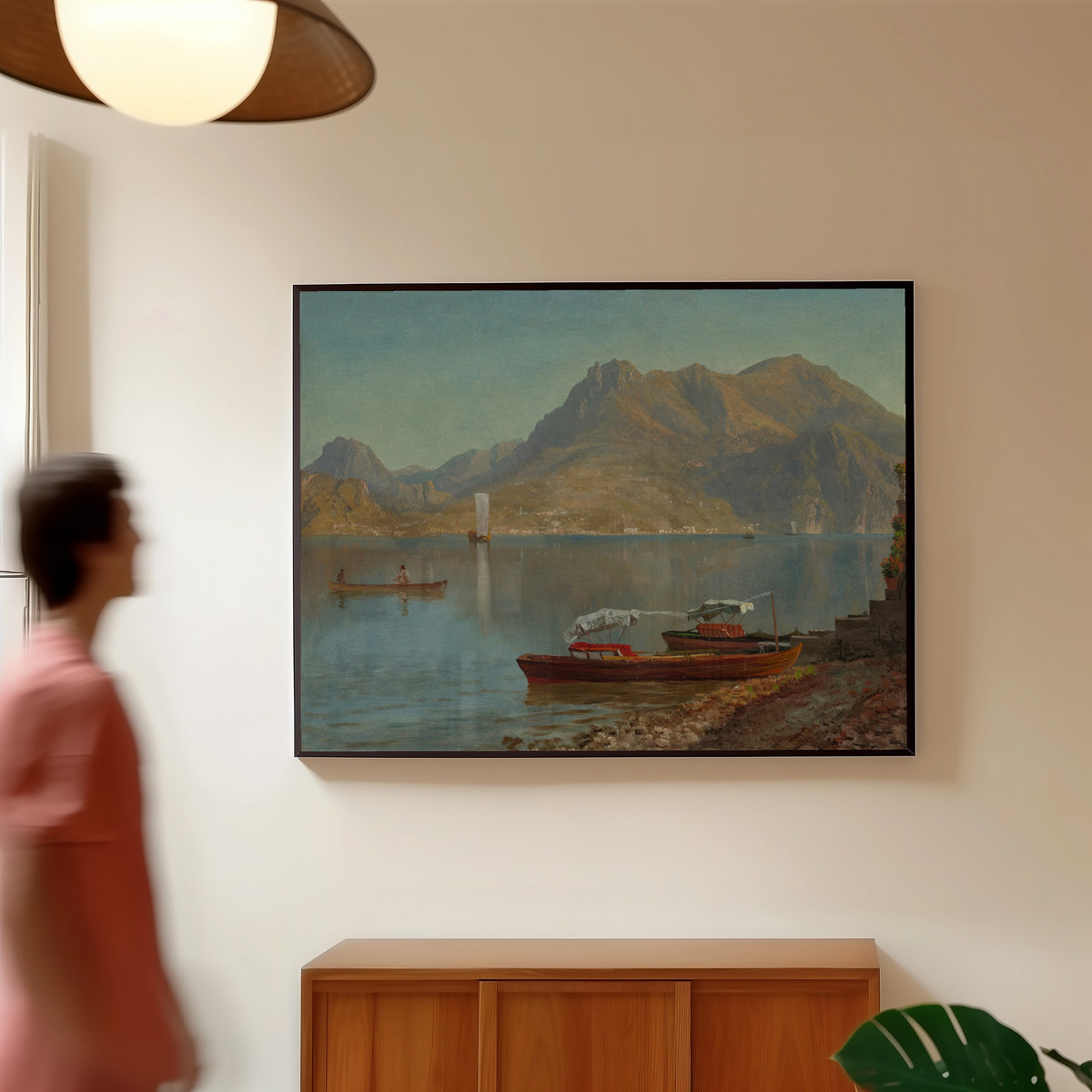 Framed art print of Lake Como by Albert Bierstadt, in a slim black frame on a warm wall in a sunlit room