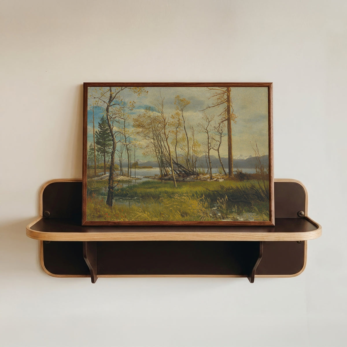 Framed art print of Lake Tahoe by Albert Bierstadt, in a dark wood frame resting on a wall shelf