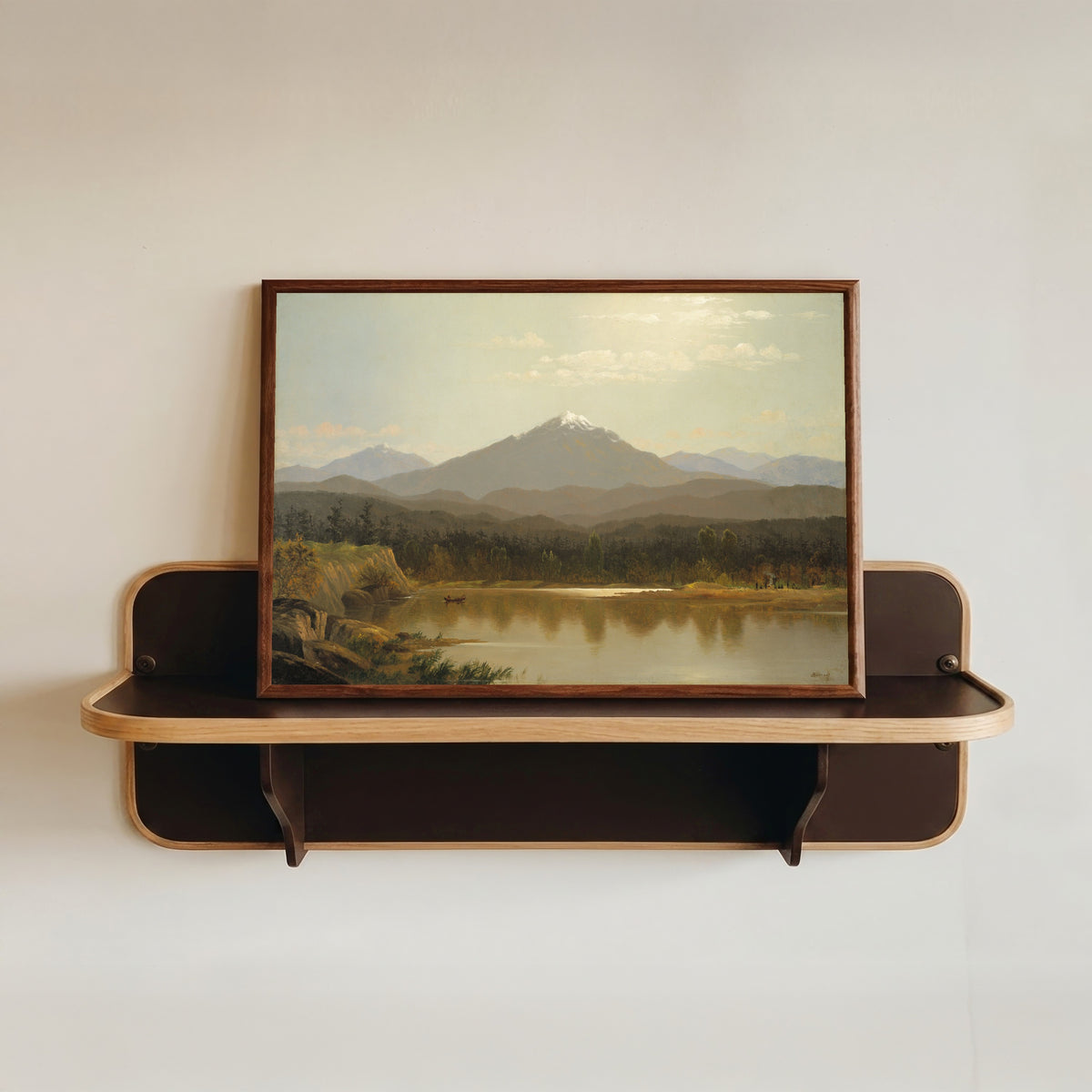 Framed art print of Laramie Peak by Albert Bierstadt, in a dark wood frame resting on a wall shelf