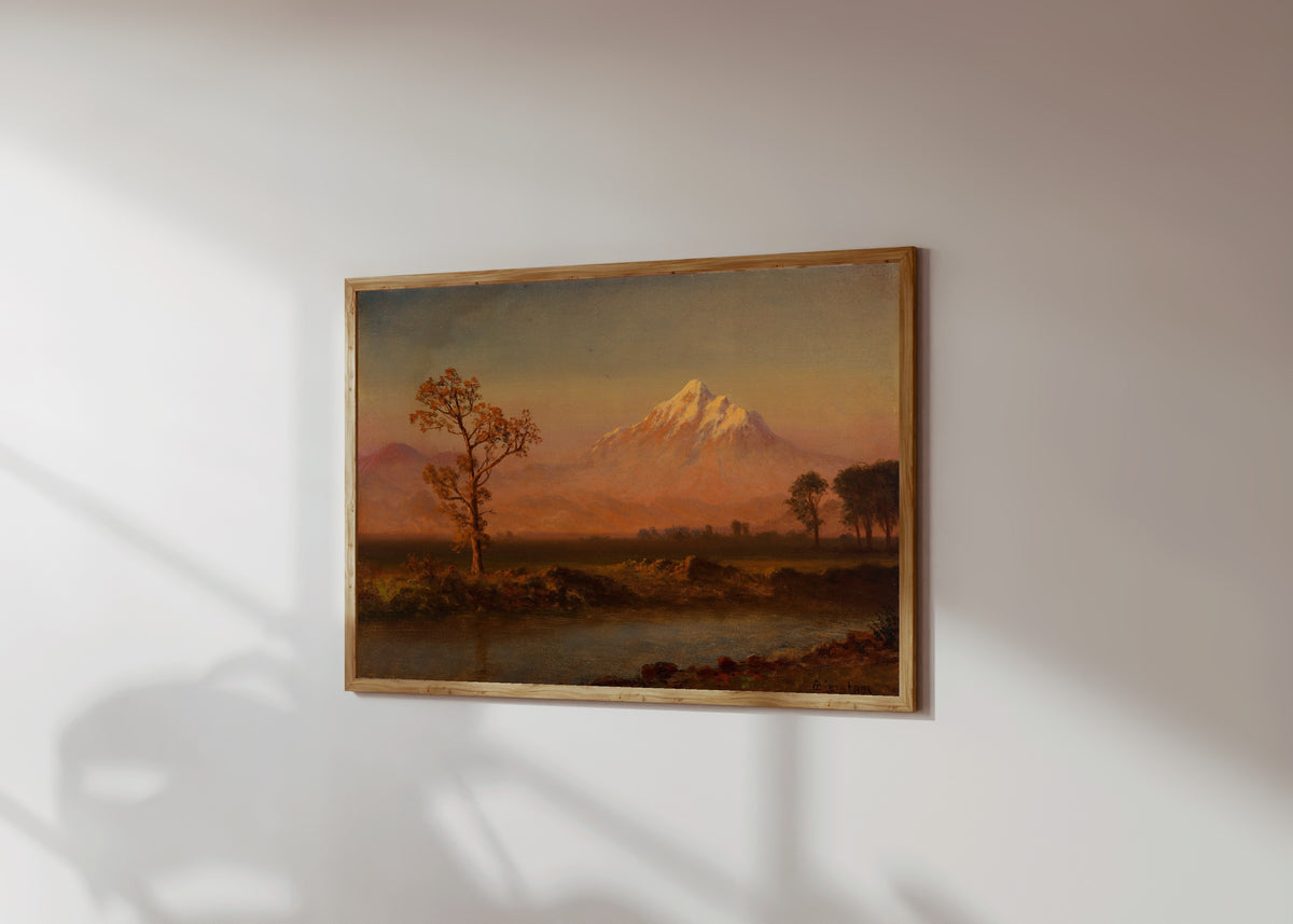 Framed art print of Mount Hood by Albert Bierstadt, in a light wood frame on a sunlit white wall, seen at a slight angle