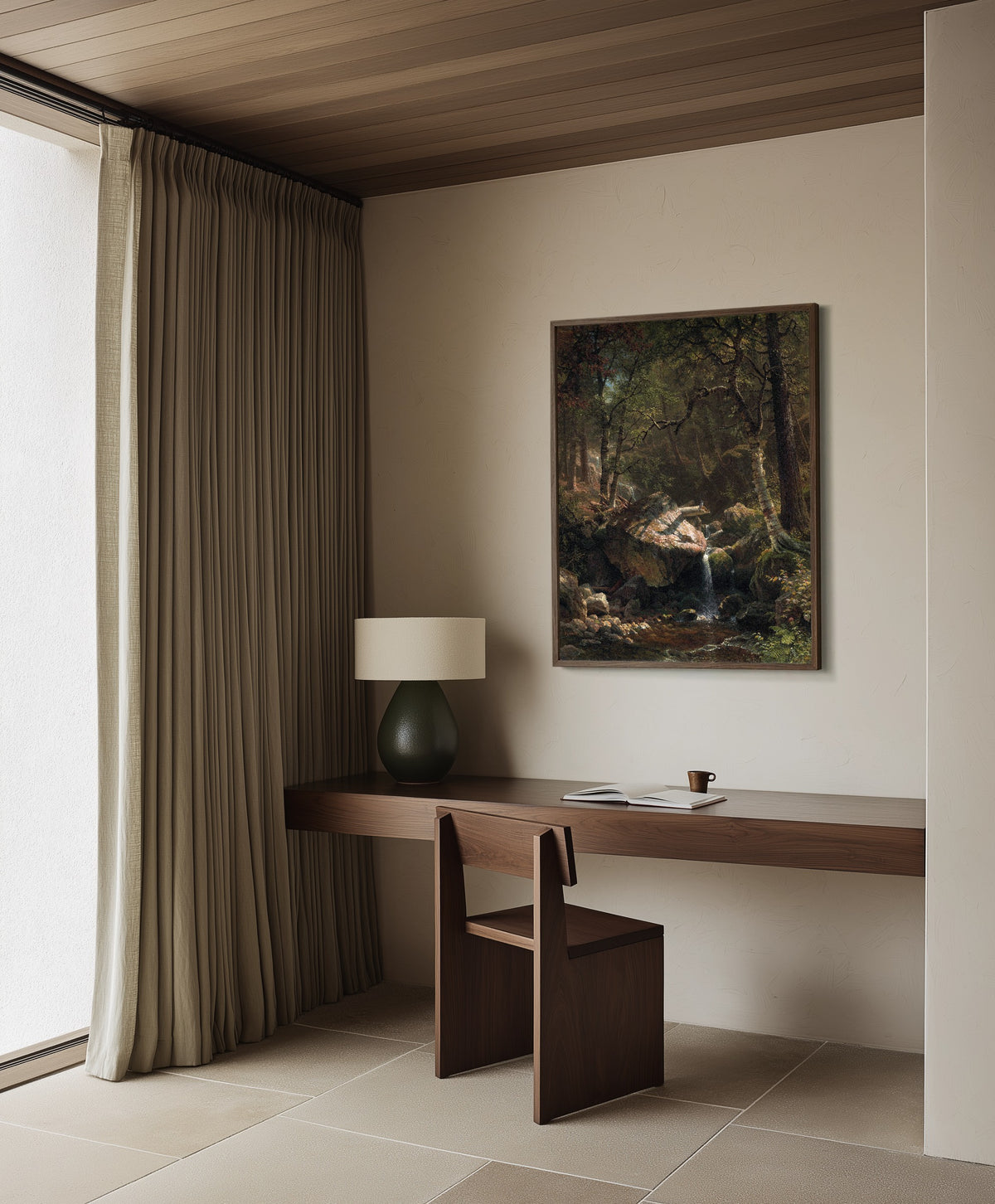 Framed art print of Mountain Brook by Albert Bierstadt, in a dark wood frame on a plaster wall above a walnut desk