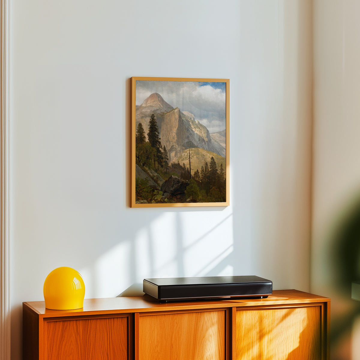 Framed art print of North Dome, Yosemite Valley by Albert Bierstadt, in a light wood frame on a white wall above an orange sideboard