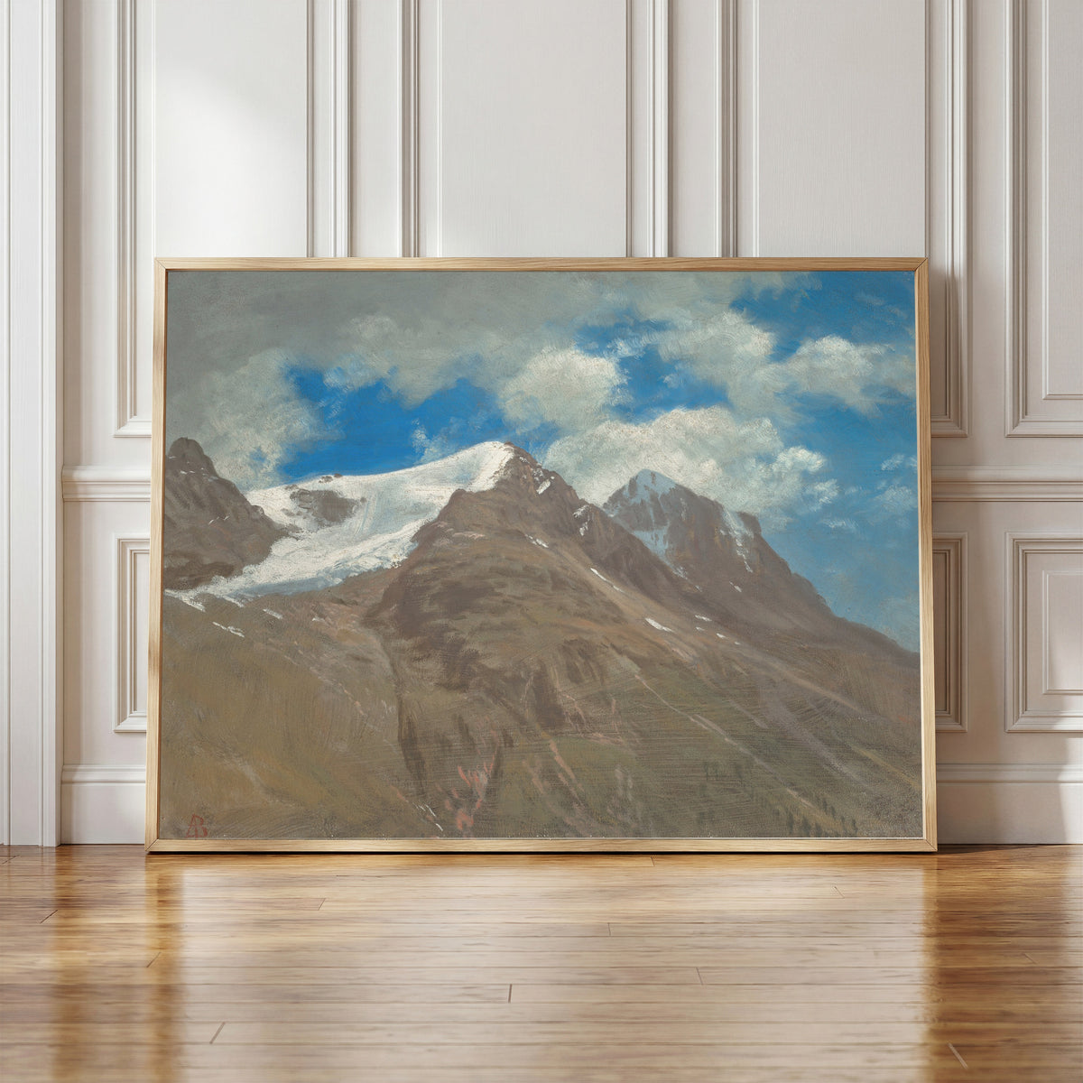 Framed art print of Peaks in the Rockies by Albert Bierstadt, in a light wood frame leaning against a panelled white wall