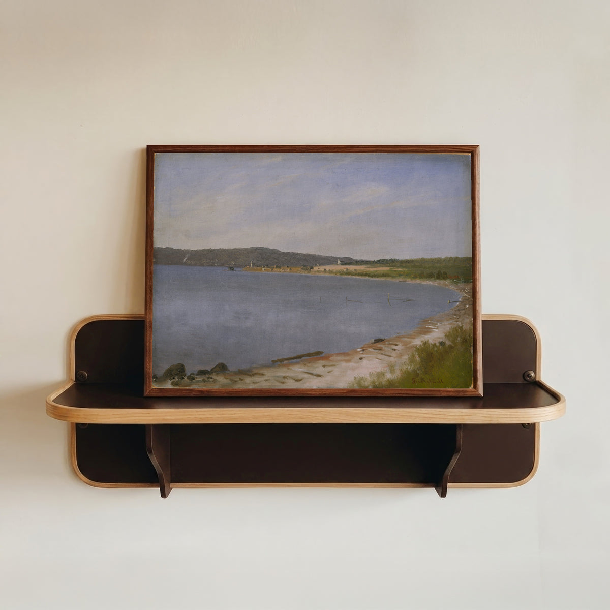 Framed art print of San Francisco Bay by Albert Bierstadt, in a dark wood frame resting on a wall shelf