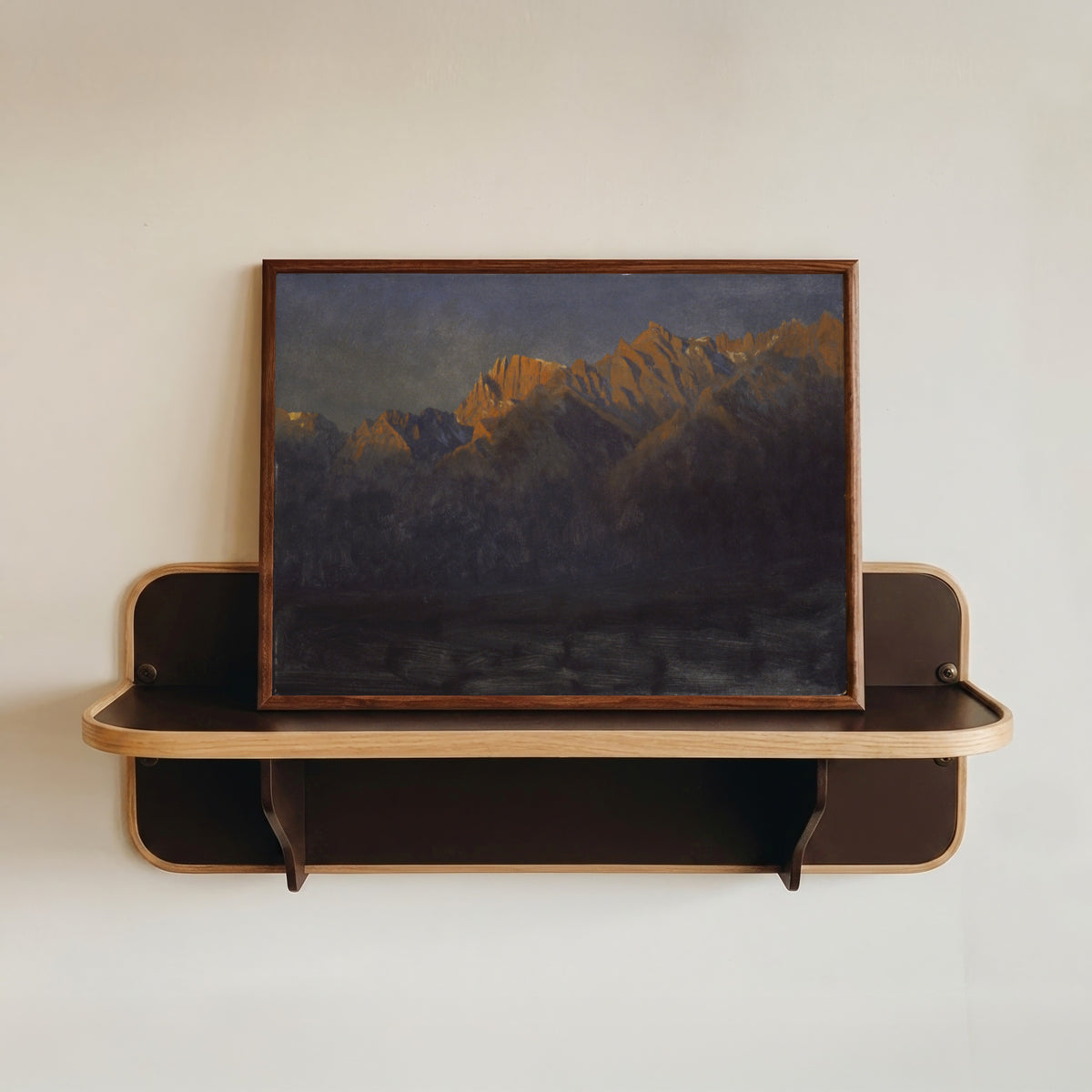 Framed art print of Sunrise in the Sierras by Albert Bierstadt, in a dark wood frame resting on a wall shelf