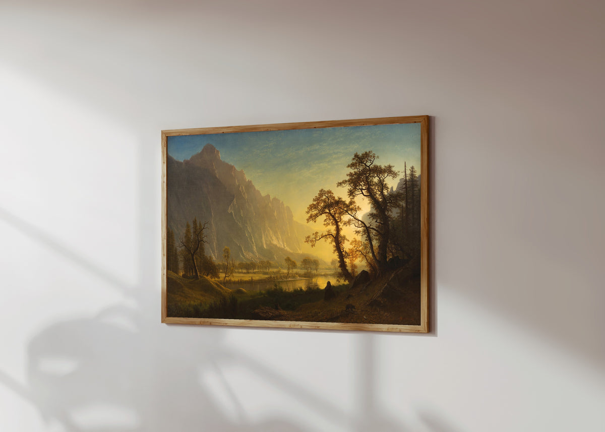 Framed art print of Sunrise, Yosemite Valley by Albert Bierstadt, in a light wood frame on a sunlit white wall, seen at a slight angle